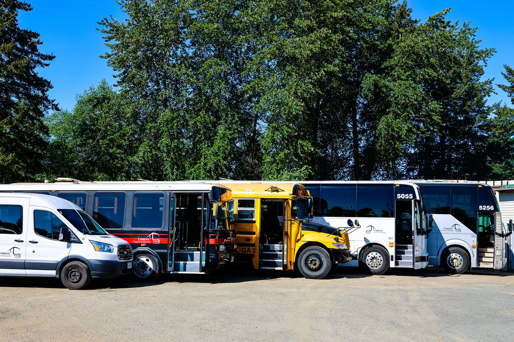 The Comox Coach & Shuttle fleet — highway coaches, activity bus, and passenger van lined up and ready